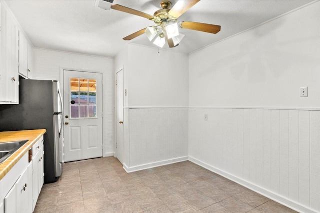 kitchen featuring ceiling fan, sink, and white cabinets