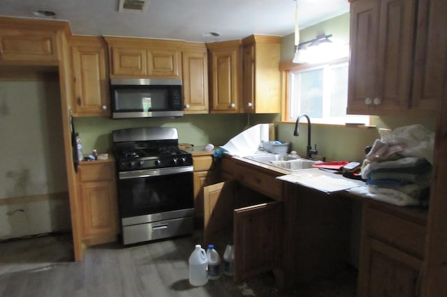 2114 11th St, Port Neches, TX 77651 - kitchen featuring appliances with stainless steel finishes, a sink, light wood finished floors, and light countertops
