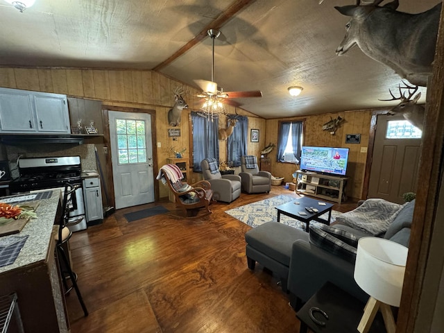 living room featuring ceiling fan, dark hardwood / wood-style flooring, vaulted ceiling, and wooden walls