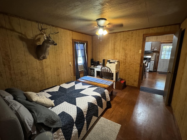 bedroom featuring ceiling fan, wooden walls, and dark wood-type flooring