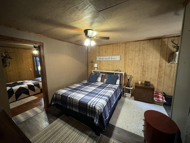 bedroom featuring ceiling fan, dark hardwood / wood-style floors, and wooden walls