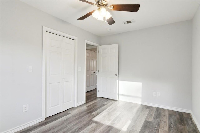 unfurnished bedroom featuring ceiling fan, light hardwood / wood-style floors, and a closet