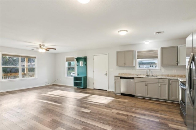 kitchen featuring ceiling fan, dark hardwood / wood-style flooring, sink, gray cabinetry, and stainless steel appliances