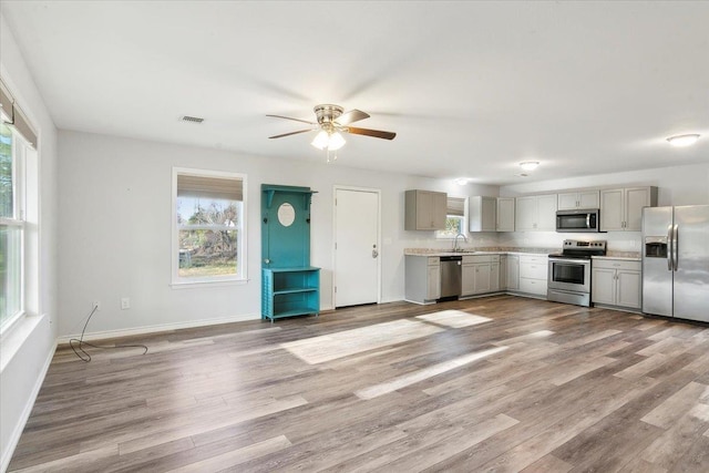 kitchen featuring sink, light wood-type flooring, appliances with stainless steel finishes, and gray cabinetry