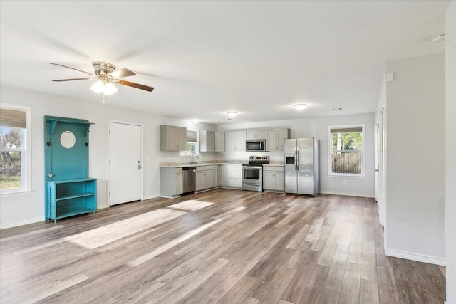 kitchen featuring appliances with stainless steel finishes, sink, light wood-type flooring, ceiling fan, and gray cabinetry