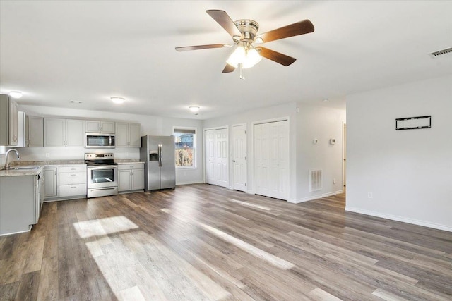 kitchen featuring sink, hardwood / wood-style floors, gray cabinetry, and stainless steel appliances