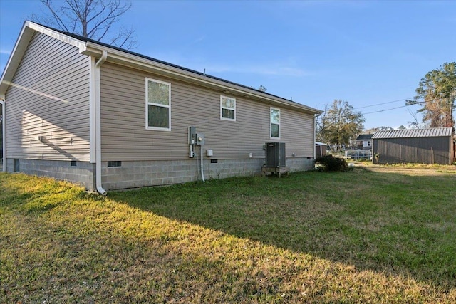 rear view of property featuring cooling unit and a lawn