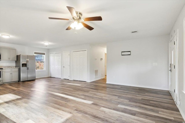 unfurnished living room with ceiling fan and wood-type flooring