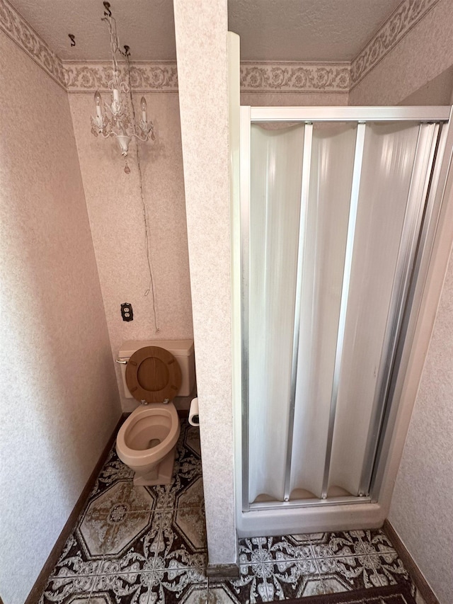 bathroom with toilet, an inviting chandelier, a textured ceiling, and walk in shower