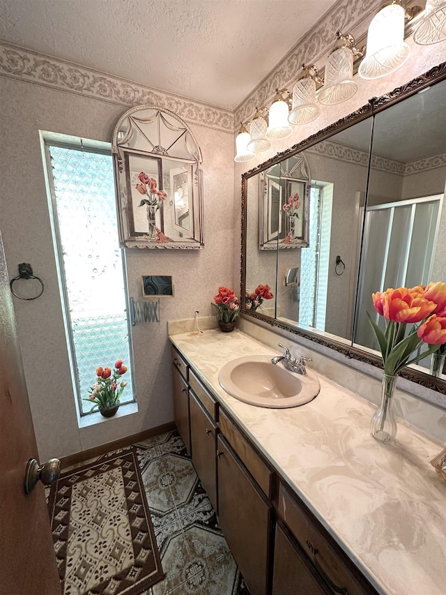 bathroom with tile patterned flooring, vanity, a shower with shower door, and a textured ceiling