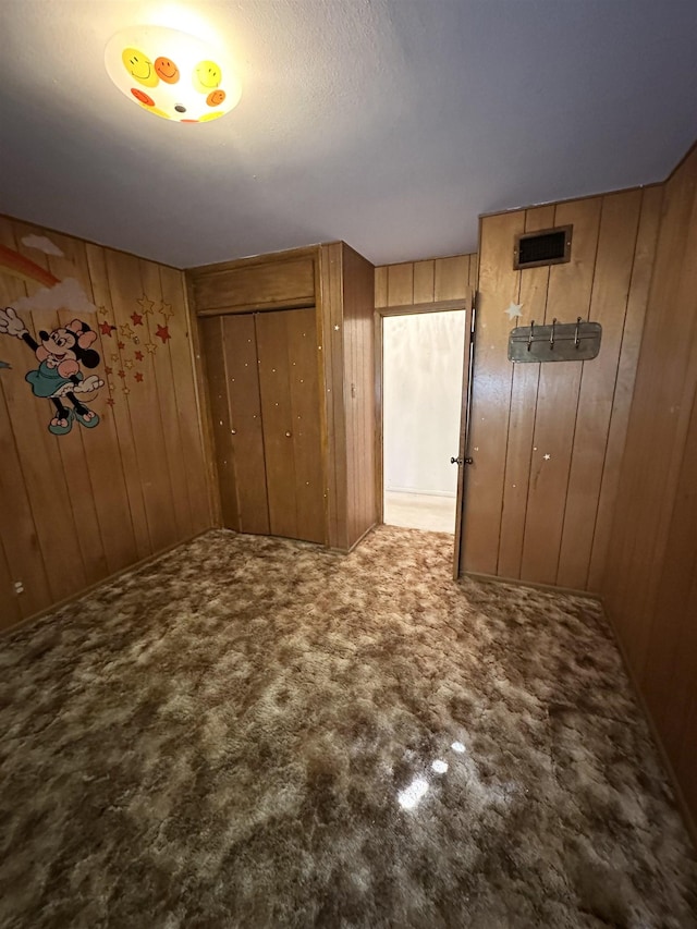 interior space with wooden walls, a closet, and light colored carpet