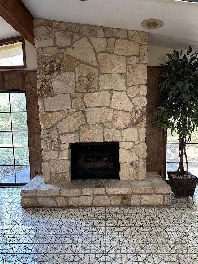 details with beam ceiling, a stone fireplace, and wooden walls