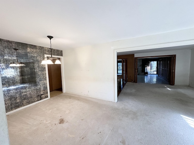 empty room with a notable chandelier and carpet floors