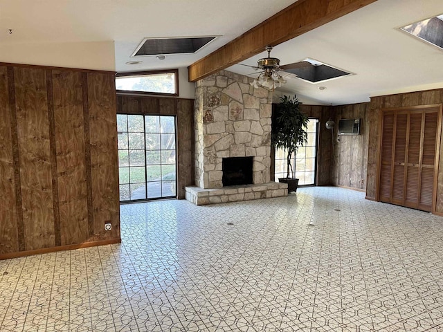 unfurnished living room featuring a fireplace, vaulted ceiling with beams, ceiling fan, and wooden walls