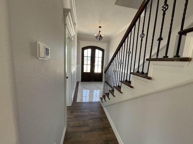 entryway featuring dark wood-type flooring, french doors, a chandelier, and ornamental molding