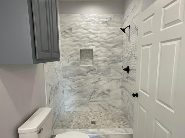 bathroom with a tile shower and toilet