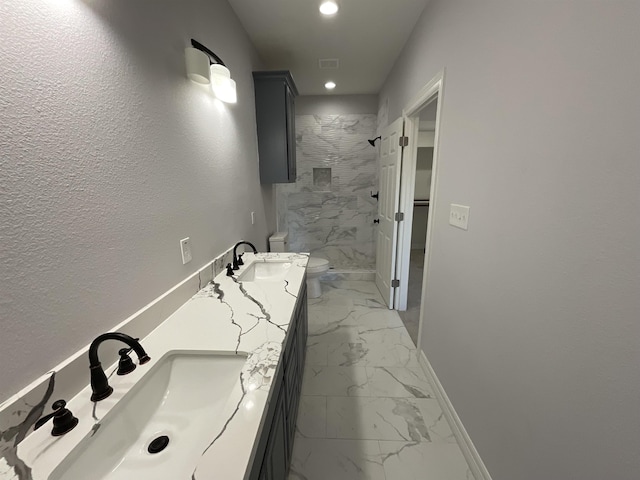 bathroom with a tile shower, vanity, and toilet