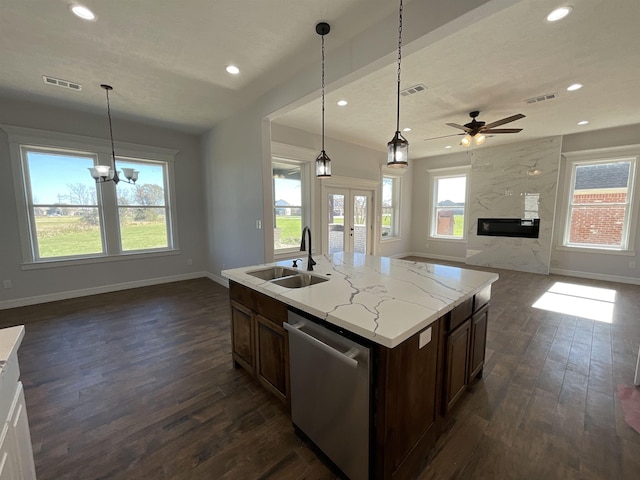 kitchen featuring dishwasher, pendant lighting, an island with sink, and sink