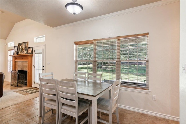 tiled dining area featuring a tile fireplace, vaulted ceiling, and crown molding