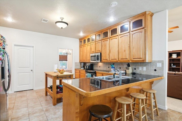 kitchen featuring kitchen peninsula, light tile patterned floors, stainless steel appliances, and a breakfast bar area