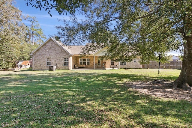 rear view of house with cooling unit and a lawn