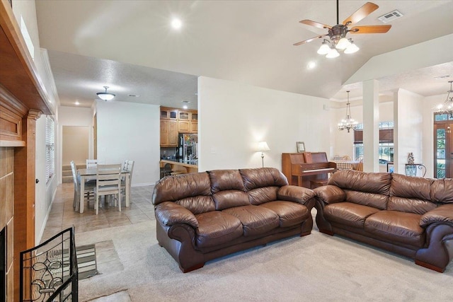 carpeted living room with ceiling fan with notable chandelier and vaulted ceiling