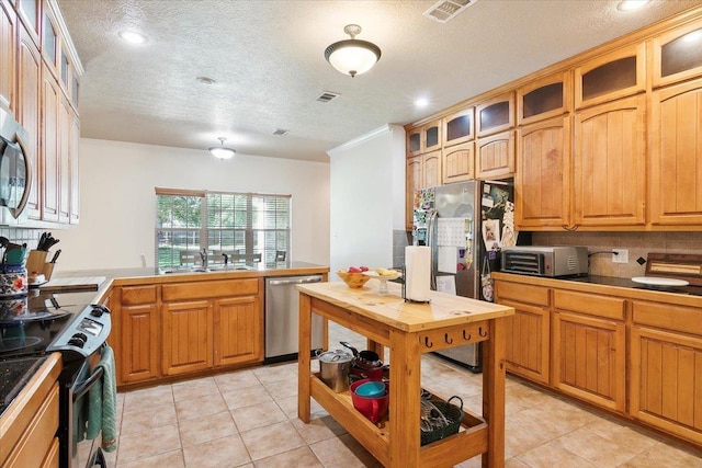 kitchen featuring decorative backsplash, appliances with stainless steel finishes, a textured ceiling, sink, and light tile patterned floors