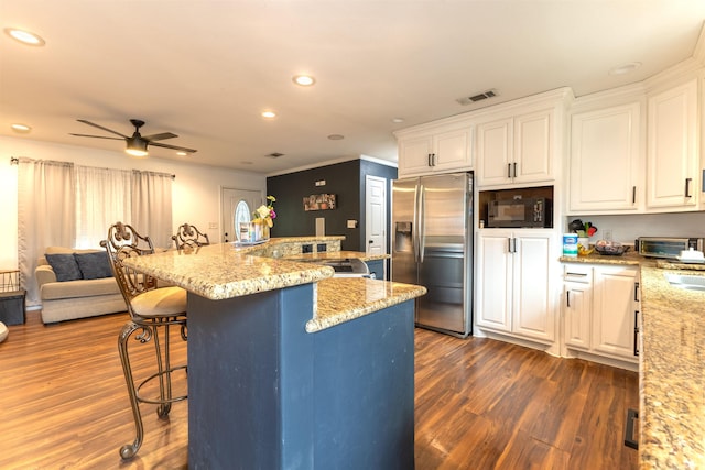 2315 Granger Dr, Bridge City, TX 77611 - kitchen with stainless steel refrigerator with ice dispenser, a breakfast bar area, open floor plan, black microwave, and white cabinets