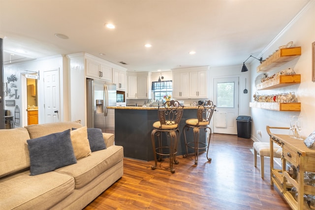 2315 Granger Dr, Bridge City, TX 77611 - kitchen with ornamental molding, stainless steel refrigerator with ice dispenser, white cabinets, dark wood-style flooring, and a breakfast bar