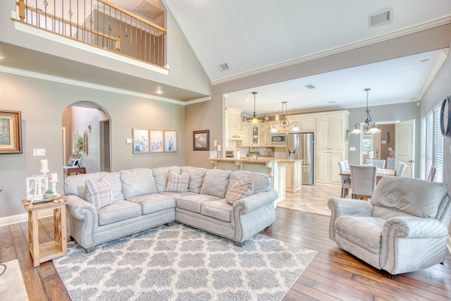 living room with crown molding, high vaulted ceiling, and hardwood / wood-style flooring