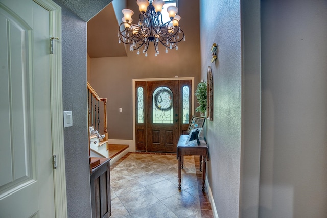 entryway featuring light tile patterned floors, a towering ceiling, and an inviting chandelier