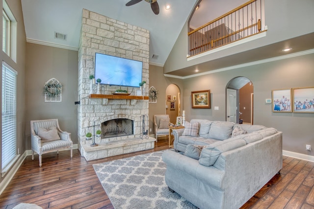 living room with ceiling fan, dark hardwood / wood-style floors, a stone fireplace, and high vaulted ceiling