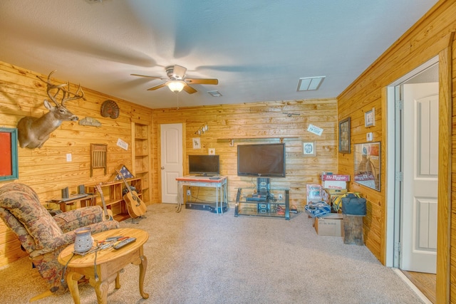 carpeted living room featuring ceiling fan and wood walls