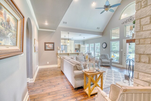 living room featuring high vaulted ceiling, ceiling fan with notable chandelier, sink, crown molding, and hardwood / wood-style flooring