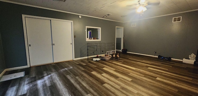 unfurnished bedroom with a closet, ceiling fan, crown molding, and dark wood-type flooring