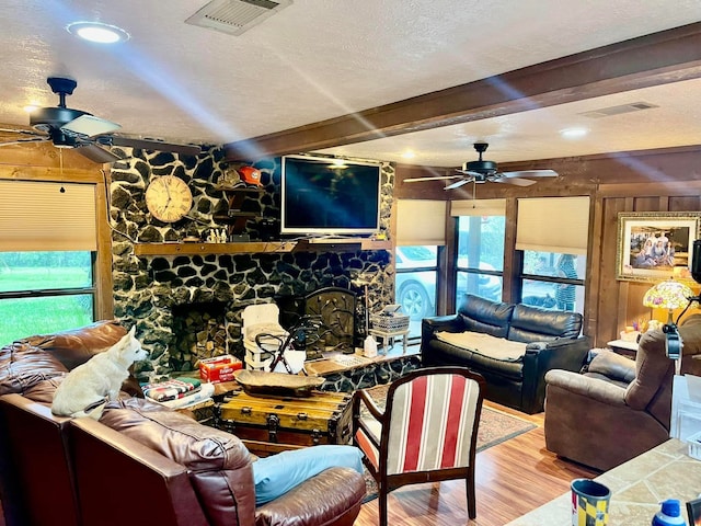 living room with beam ceiling, a fireplace, a textured ceiling, and hardwood / wood-style flooring