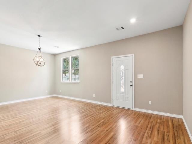 entryway with light wood-type flooring, visible vents, baseboards, and an inviting chandelier