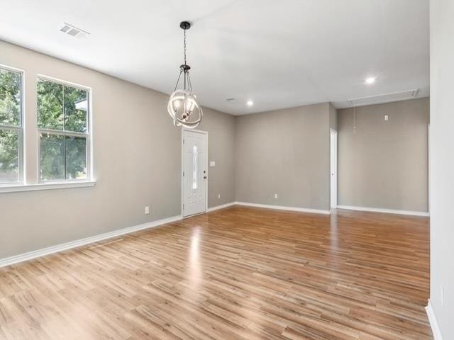 spare room featuring wood finished floors, visible vents, baseboards, attic access, and recessed lighting