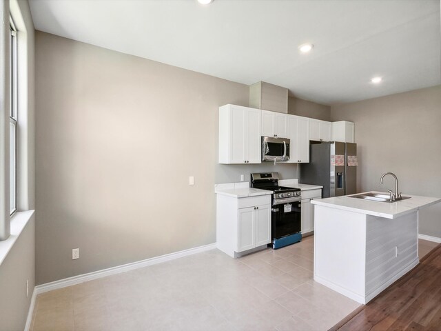 kitchen with white cabinets, appliances with stainless steel finishes, baseboards, and a sink