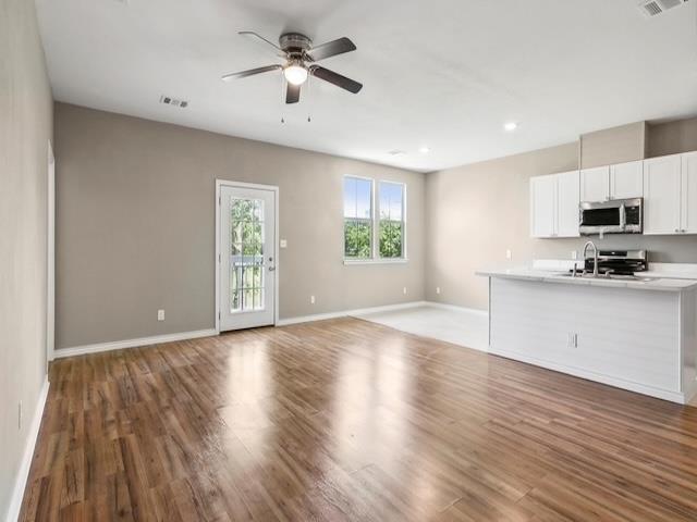 unfurnished living room featuring visible vents, baseboards, light wood-type flooring, and ceiling fan