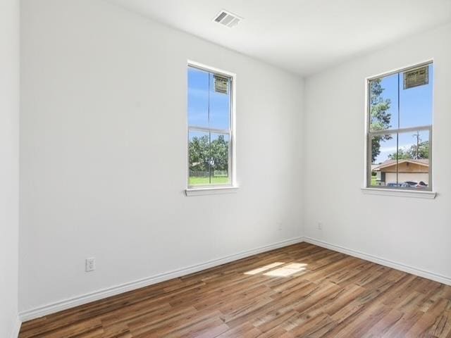 empty room featuring visible vents, baseboards, and wood finished floors