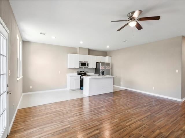 unfurnished living room with light wood finished floors, visible vents, baseboards, ceiling fan, and recessed lighting