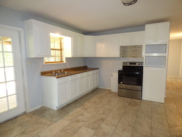 kitchen with white cabinets, light tile patterned flooring, sink, and stainless steel range with electric cooktop