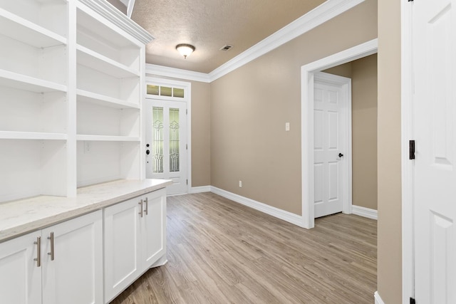 interior space with a textured ceiling, light hardwood / wood-style flooring, and crown molding