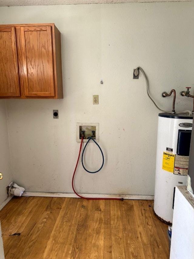 laundry area with cabinets, electric dryer hookup, water heater, hookup for a washing machine, and wood-type flooring