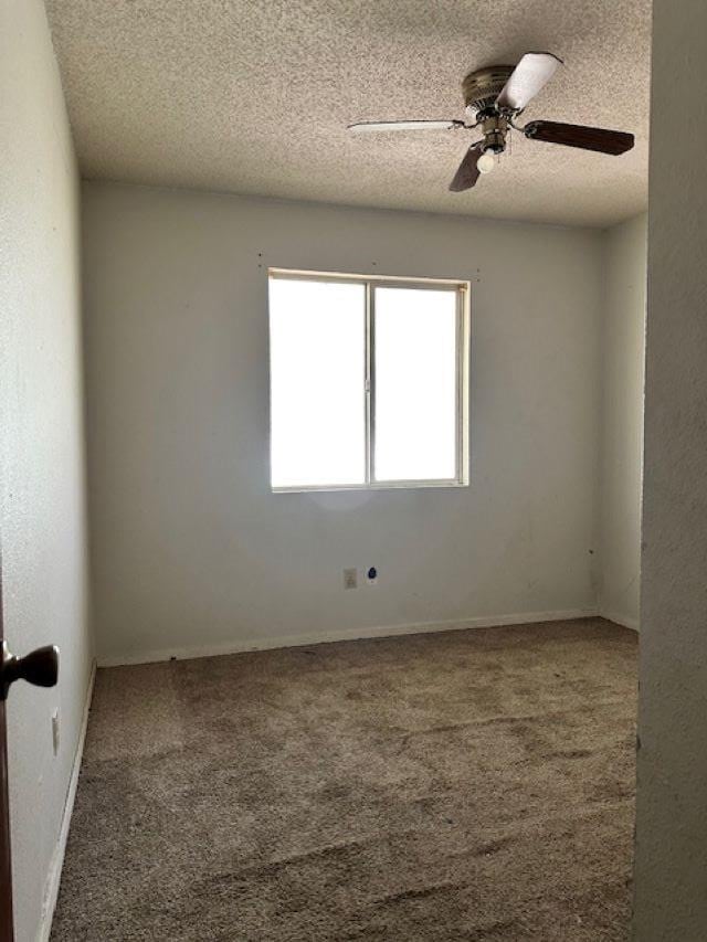 carpeted spare room featuring ceiling fan and a textured ceiling