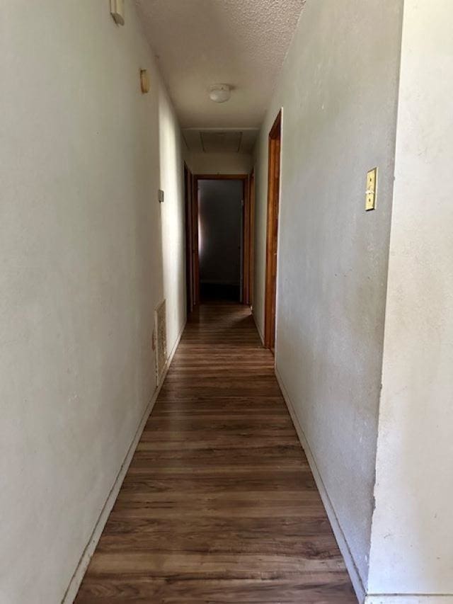 corridor featuring a textured ceiling and dark wood-type flooring