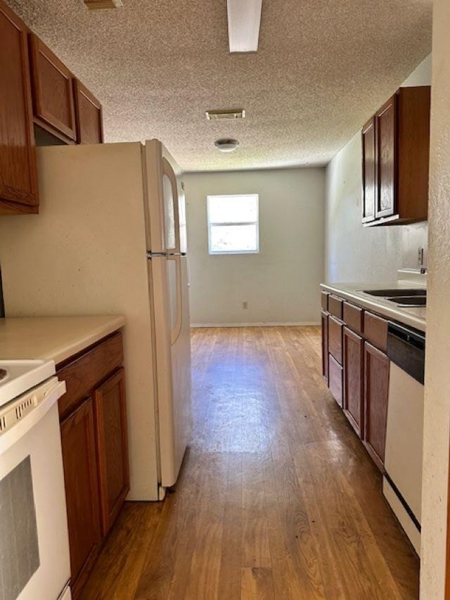 kitchen featuring sink, dishwasher, light hardwood / wood-style floors, a textured ceiling, and range