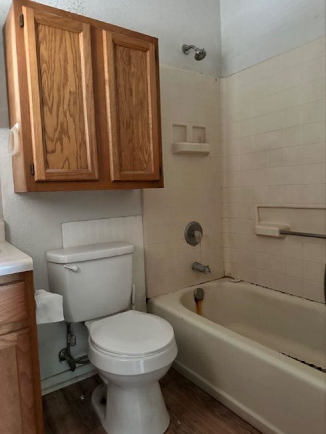 full bathroom with tiled shower / bath, toilet, vanity, and hardwood / wood-style flooring