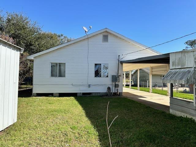 rear view of property with a carport and a lawn